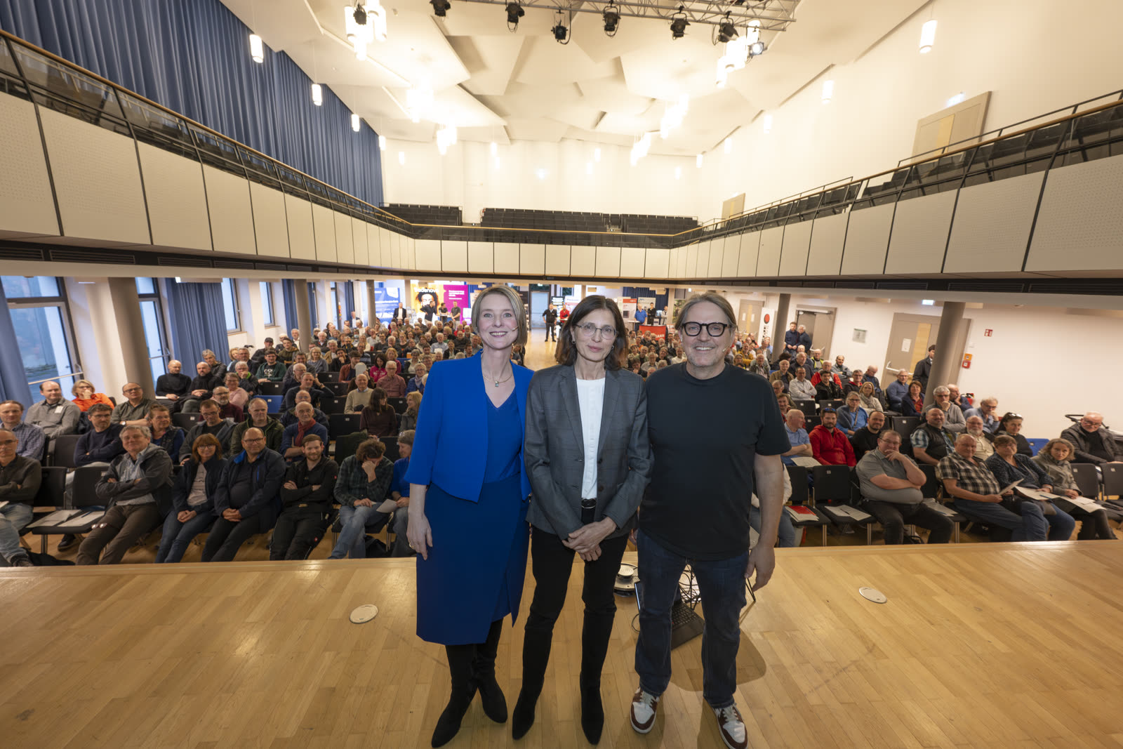 Anja Floetenmeyer-Woltmann mit zwei Gastgeberinnen auf der Bühne vor vollem Saal beim Wärmepumpen-Infotag in Freiburg. Foto: Stadt Freiburg