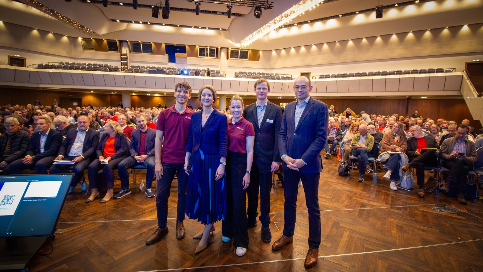Gruppenbild mit dem Team der Stadt Würzburg vor vollem Saal