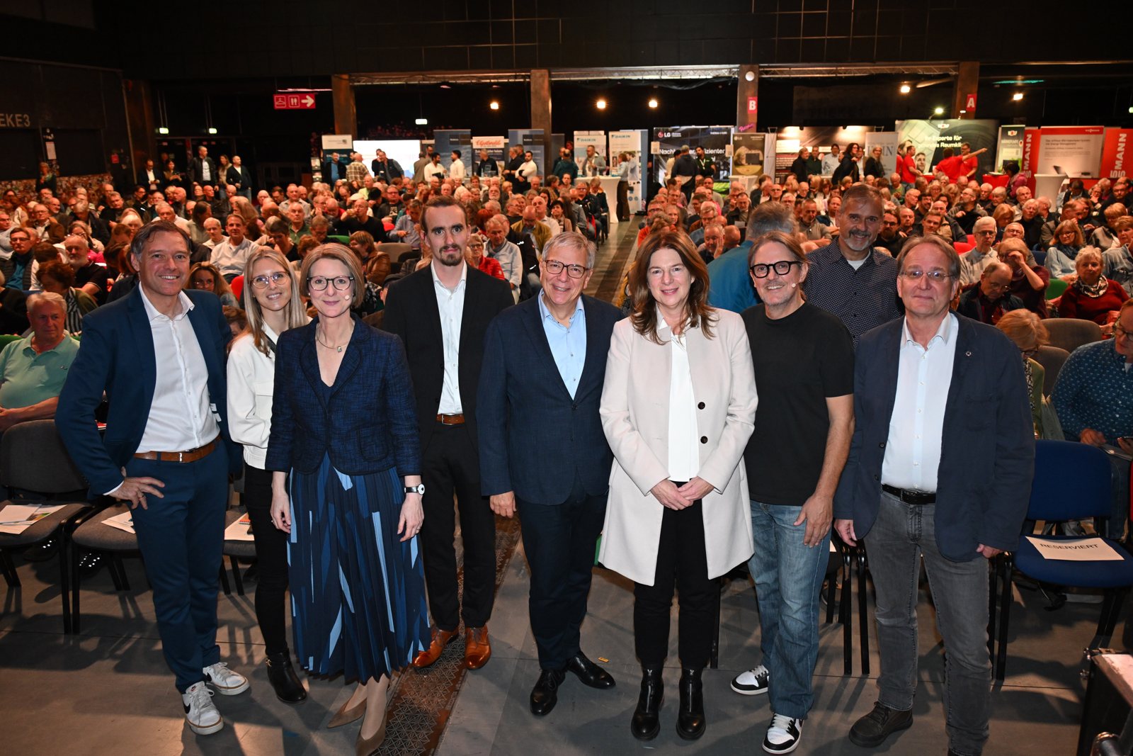 Gruppenbild vor voller Halle: Christian Skerka, Hannah Bruchhaus, Anja Floetenmeyer-Woltmann, Dr. Andreas Bott, Oberbürgermeister Gert-Uwe Mende, Bürgermeisterin Christiane Hinninger, Carsten Herbert, Dr. Klaus Friedrich